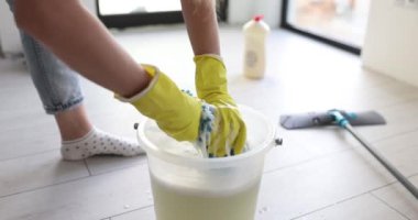 Lastik eldivenli temizlikçi kadın odada kovayla bez sıkıyor. Temizlikçilerle çalışan hizmetçi.