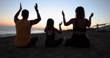 Aile, plajda birlikte vakit geçirir ebeveynler ve çocuklar meditasyon yapar ve yoga yaparlar. Aile uyumu ve rahatlama