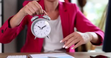 İş kadını, işyerindeki 10 kilit için alarmlı saate işaret ediyor. Çalışma takvimi yönetimi ve fazla mesai ve son teslim tarihi planlanıyor