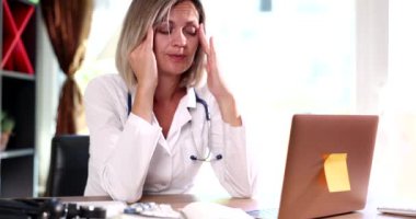 İş yerinde başı ağrıyan yorgun kadın doktor. Yorgun bir terapist doktor. Baş ağrısı çekiyor ve acı çekiyor.