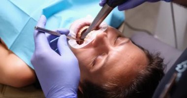 Kapalı diş hekimi, dişçi kliniğinde dişlerini tedavi ediyor. Diş donanımı ve hijyenik temizlik prosedürü