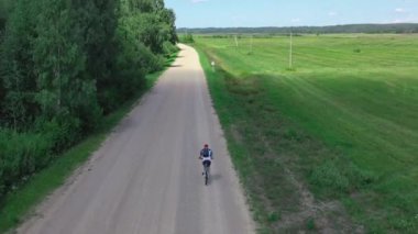 Genç bisikletçiler şehir manzarası dışında yol boyunca gezerler. Doğada aktif dinlenme ve spor