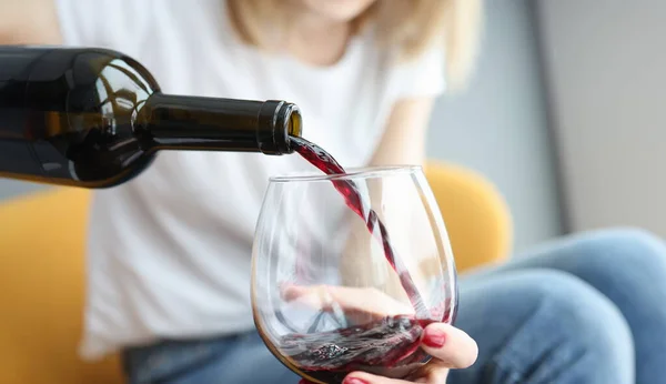 Woman pouring red wine into glass closeup. Quality alcohol concept