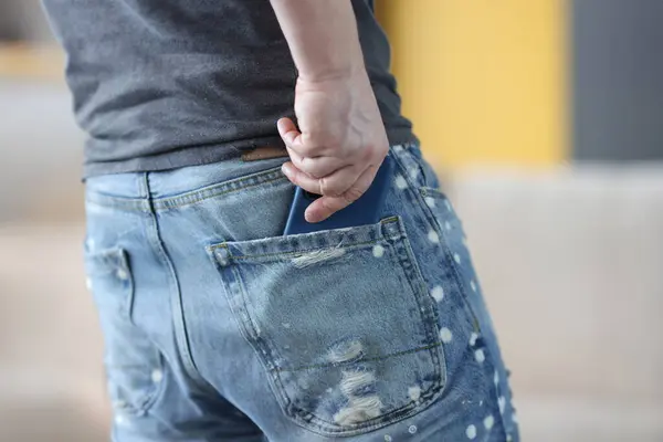 Man putting phone in his jeans pocket closeup. How to carry cell phone concept