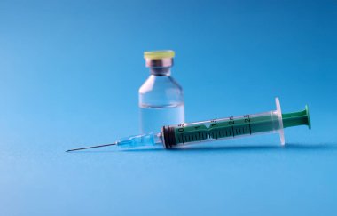 Mavi arka planda ilaç kavanozu ve şırınga yakın plan. Covid19 konseptine karşı aşı