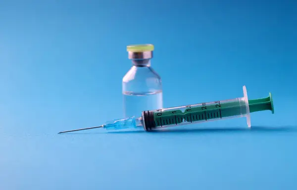 Closeup of medicine jar and syringe on blue background. Vaccination against covid19 concept