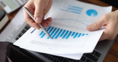 İş adamı grafiklerdeki iş istatistiklerini inceliyor. Pazarlama ve analitik kavramı