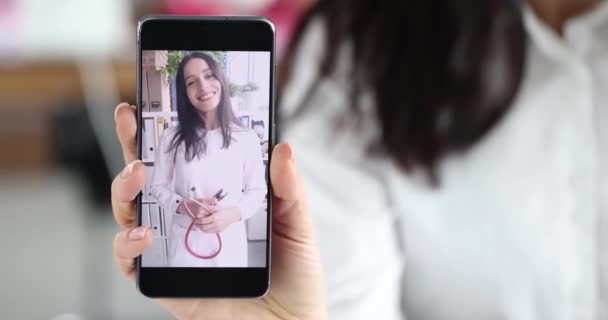 女の子はスマートフォンを持ち 医師として女性と相談しています ビデオチャットコンセプトによるセラピストによる医師の遠隔相談 — ストック動画