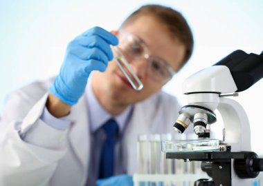 Erkek kimyager tutan tüp cam el portre taşmaları sıvı çözüm potasyum permanganat yürüten bir analiz tepki alır çeşitli kimyasal üretim kullanarak reaktifler sürümleri.