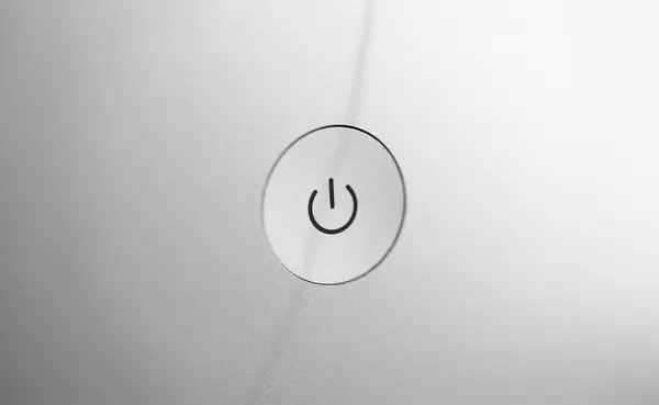 Silver coarse turn on and off button at gray blank back panel of electronic gadget closeup