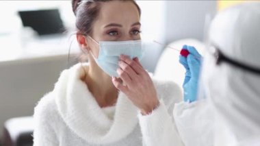 Koruyucu giysili doktor evdeki bir hastadan PCR testi alır. Doktor ya da hemşire hastaya örnek verecek.