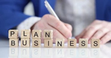 Bir işadamı, ön plandaki tahta küplere yazı yazdığını yazıyor. Sunum ve teklif