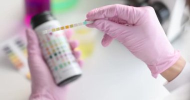 Eldivenli eller, test şeritlerini tutun, yakın çekim, yavaş çekim. Su ph göstergesi, tıbbi laboratuvar, diyabet