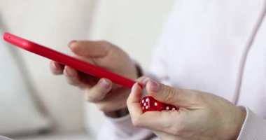 Bir kadın akıllı telefon kullanır ve zar oyunlarını çözer, yakın plan eller. Online kumarhane bahisleri, kumar bağımlılığı