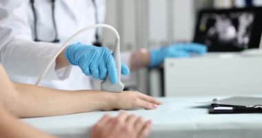 Kadın bir doktor, elinin eklemlerinin ultrasonunu çeker. Yakın çekim, yavaş çekim. El damarlarının klinik incelemesi