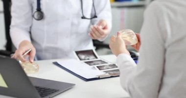 Bir doktor bir kadına silikon göğüs implantı gösterir, yakın çekim, yavaş çekim. Estetik ameliyat, göğüs kanseri.