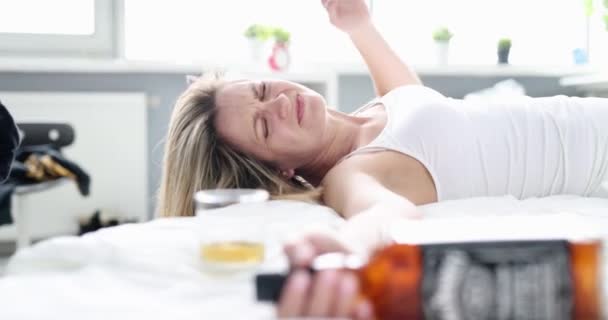 喝醉了的女人 床上有一瓶酒 特写镜头 聚会后早上醒来 宿醉头疼 — 图库视频影像
