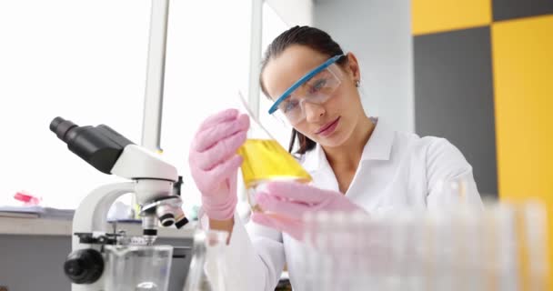 Een Vrouwelijke Chemicus Een Laboratorium Kijkt Naar Een Gele Vloeistof — Stockvideo