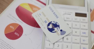 Hesap makinesinin üzerinde beyaz plastik bir banka kartı var, yakın plan. Mevduat için elverişli koşullar, kredi geçmişi