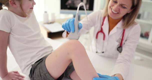 Ein Lächelnder Arzt Macht Dem Mädchen Einen Ultraschall Des Knies — Stockvideo