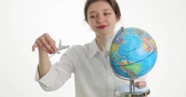 Genç bir kadın elinde bir küre ve oyuncak bir uçak tutuyor, yakın plan. Açık kenar kavramı, seyahat, yavaş çekim