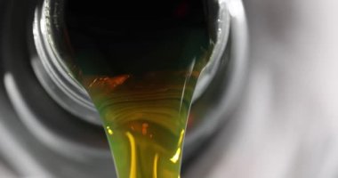 Sarı yağ akışı plastik bir teneke kutudan, yakın plandan geliyor. Yağ değişimi, yakıt eksikliği.