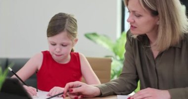 Bir kadın çocuğun ders almasına yardım eder, yakın plan. Okulda bir anaokulu öğrencisiyle bireysel dersler.