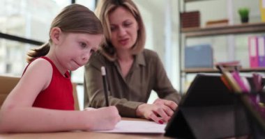 Sınıftaki kız öğretmenin yanında bir kalemle yakın plan yazıyor. Anaokulu çocuklarını yazmayı öğrenmek