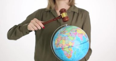 Bir iş kadını bir yargıcın çekicini ve bir küreyi elinde tutuyor. Yakın plan. Kavram, uluslararası mahkeme, insan hakları