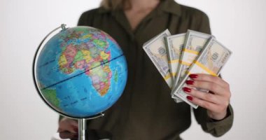Bir iş kadınının elinde bir deste dolar ve yakın plan bir dünya var. Uluslararası mali yardımı kabul et