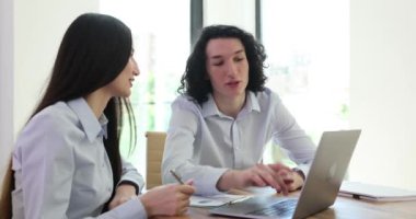 Ofisteki genç adam ve kadın dizüstü bilgisayara bakıp söylüyorlar. Beyin fırtınası, bir meslektaşa destek