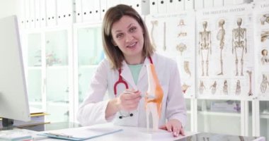 Ortopedik doktor bacağındaki eklemlerin hareketliliğinden bahsediyor, yakın plan. Dizin anatomik modeli.