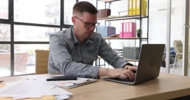 Ofiste laptopunu daktilo eden uykulu bir iş adamı, yakın plan. İş yerinde uyuşukluk, takip