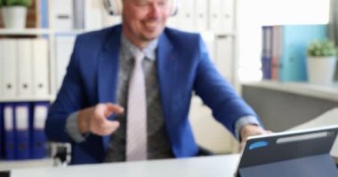 İşadamı dijital tabletin önünde kulaklık takıyor ve ofis 4K filminde yavaş çekimde dans etmeye başlıyor. Başarılı iş stratejisi kavramı