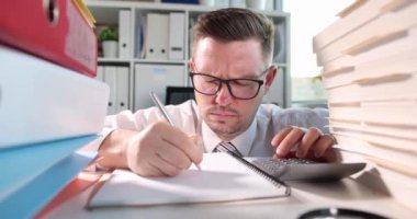 Ofisteki masada kağıtları dolduran ve ağır çekimde uyuyakalan bir adam. Fazla mesai konsepti