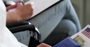 Sandalyelerde oturan ve vize başvurusu formu dolduran bir grup insan. Yurt dışına seyahat konsepti için evrak işlerinde yardım