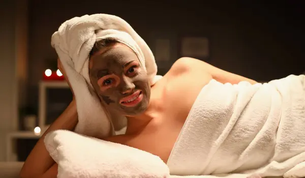Portrait of attractive female resting in spa salon. Young woman enjoying aromatic oils and clay face mask. Treatment for body. Massage cabinet. Wellness and beauty concept