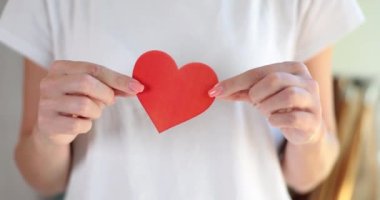 Elinde kağıttan yapılmış kırmızı kalp tutan bir kadın. Hayır kurumları gönüllü olarak yardıma muhtaç olanlara yardım ediyor.