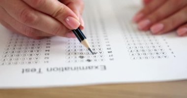 Kadın elinde kalemle sınav sorularına cevap veriyor. Test konsepti işe alınıyor