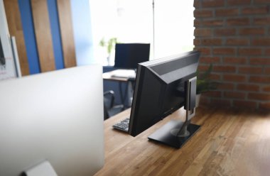 Modern bilgisayarlarla ahşap masa üzerinde şirket ofisinin yakın çekimi. İşaretli pahalı bir cihaz. İnsanlar için şık bir iş yeri. Teknoloji ve geliştirme kavramı