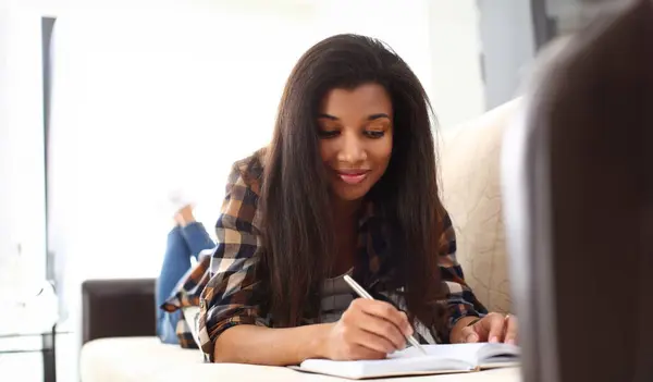 Smiling black woman write story in notebook preparing for college