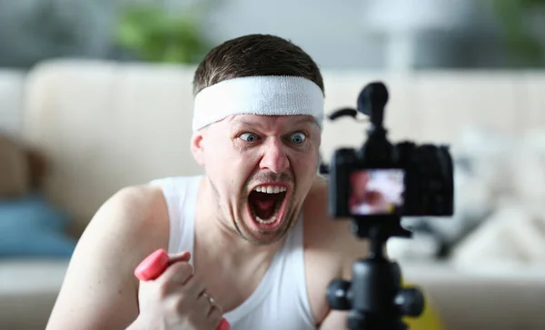 Screaming Man Holding Dumbbell Record on Camera. Aggressive Blogger Shooting Video on Digital Camcorder for Sport Blog. Shouting Guy. Bearded Man with Angry Face Head and Shoulders Photography