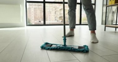 Ev hanımı ev işleri yapıyor. Isıtılmış ahşap döşemeleri ıslak paspasla temizliyor. Rutin ev işleri ve ev işi uzmanlık konsepti.