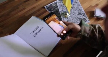 Askeri lider karşı taarruz belgelerini inceliyor ve akıllı telefondan fotoğraf çekiyor. Ukrayna ve Rusya arasındaki savaş hakkında Ukrayna verilerinin çalınması