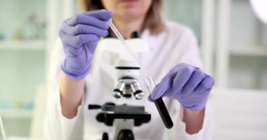 Bilim adamı siyah sıvı yağ ile test tüpüne sıvı damlatıyor. Petrol ürünlerinin kalitesi ve denetimi kontrol ediliyor