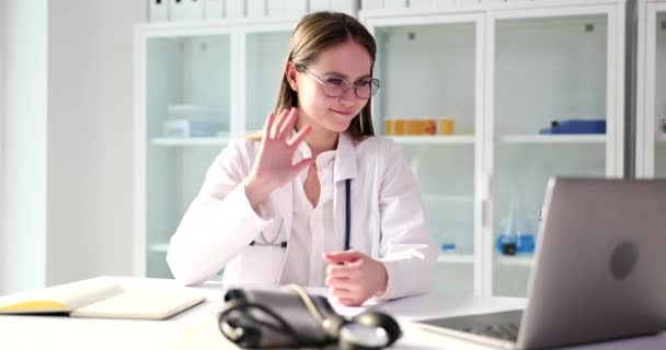 医生与病人的在线视频通话 医生在笔记本电脑前挥手问候病人 — 图库视频影像