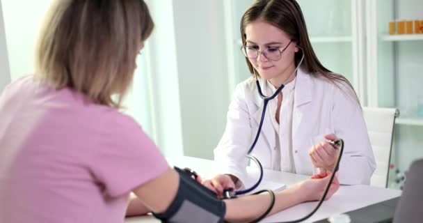 女性医師は 診療所で患者の血圧を測定します 患者は医療検査や医療保険を受けている医師と通信します — ストック動画