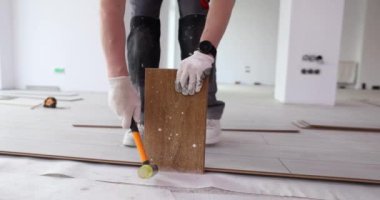 Beyaz eldivenli erkek eller çekiçle plastik çekiçle kaplanır. Yeni kaplama döşeniyor