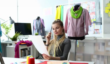 Giysi Tasarım Süreci ve Dikiş Konsepti Oluşturma. Güzel Sempstress Düşünme Elbise Sketch üzerinde çalışıyor. Modern Dressmaking Atölyesi'nde Oturan Pensive Kafkas Kadın. Terzilik İş
