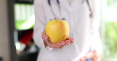 Doktor sarı elma tutuyor ve sağlıklı bir yaşam tarzı öneriyor. Beslenme uzmanı uygun beslenme öneriyor